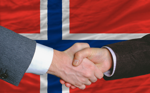 two businessmen shaking hands after good business investment  agreement in norway, in front of flag
