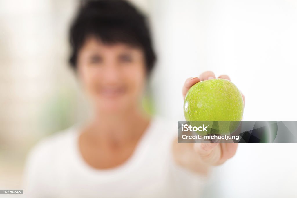 Mujer madura sosteniendo una manzana verde - Foto de stock de 40-49 años libre de derechos