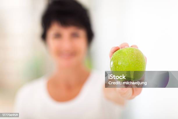 Mujer Madura Sosteniendo Una Manzana Verde Foto de stock y más banco de imágenes de 40-49 años - 40-49 años, 50-59 años, A la moda