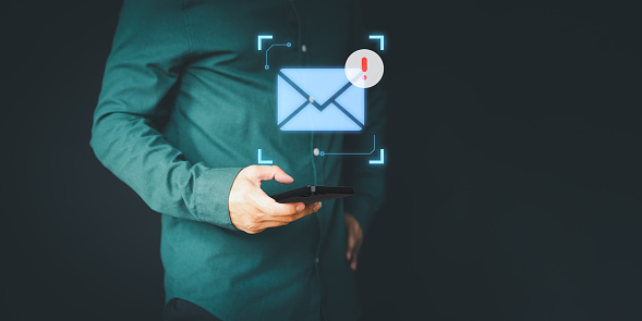 Male hand using a mobile phone with an email icon, Email alert with a caution warning sign for notification error. Security protection on the internet, junk mail, and compromised information.