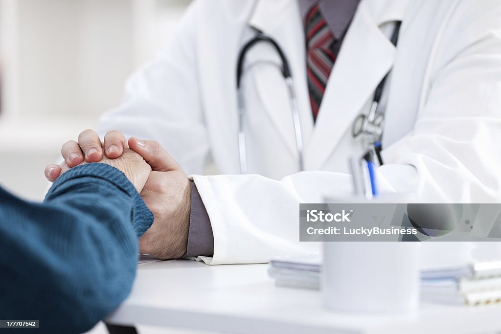 A doctor assuring his patient by holding her hand male doctor comforting patient who is in ambulance Adult Stock Photo