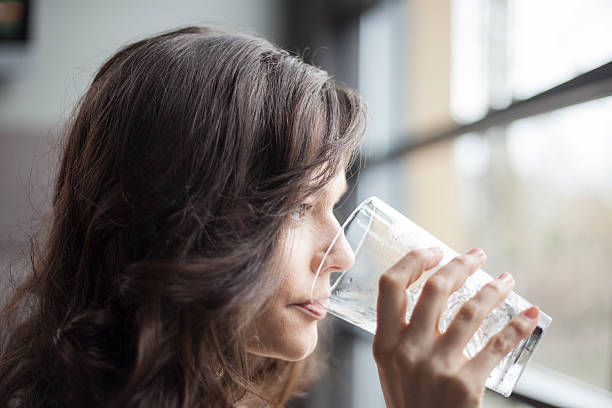 istock Woman drinking water from a pint sized glass near a window 177708376