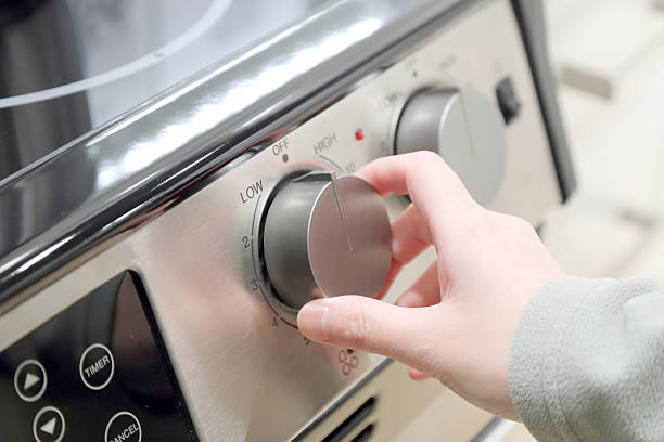 Woman turning on the oven stock photo