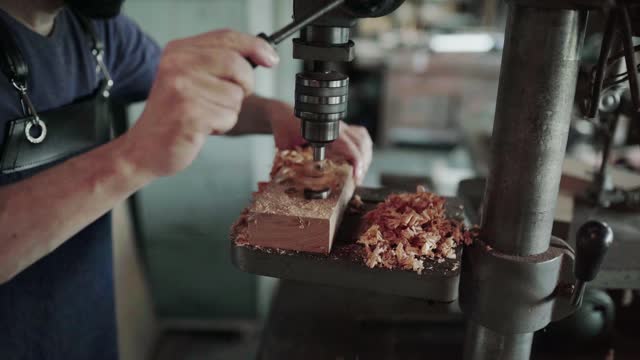 Man working on a drill press in his carpentry workshop