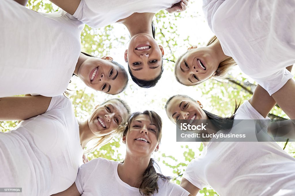 Women with heads together Group of women standing in the circle, smiling at the camera, low angle view. Circle Stock Photo