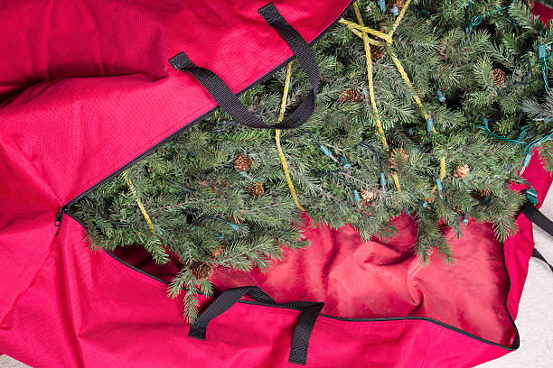 Putting the Chirstmas tree way for next year Large artificial Christmas tree being placed in red nylon zipper bag for next season christmas decoration storage stock pictures, royalty-free photos & images