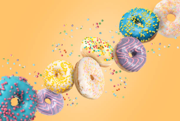 istock Many sweet tasty donuts with sprinkles falling on pale orange background 1777124820