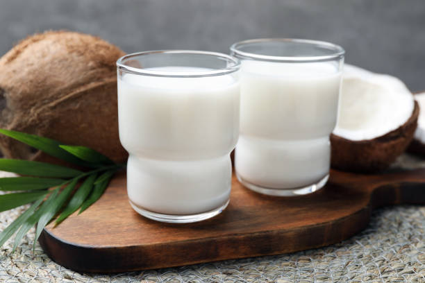 istock Glasses of delicious coconut milk, palm leaf and coconuts on table 1777124827