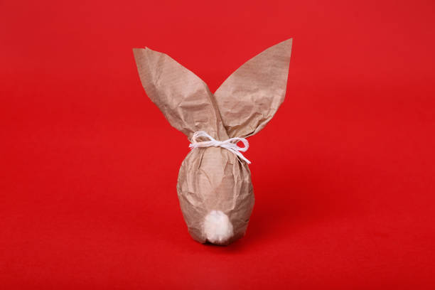 Easter bunny made of kraft paper and egg on red background