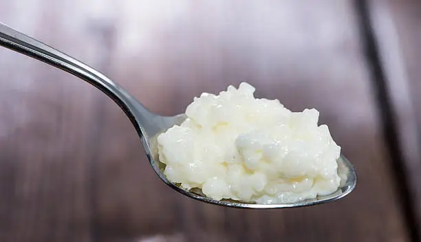 Spoon with Rice Pudding on wooden background
