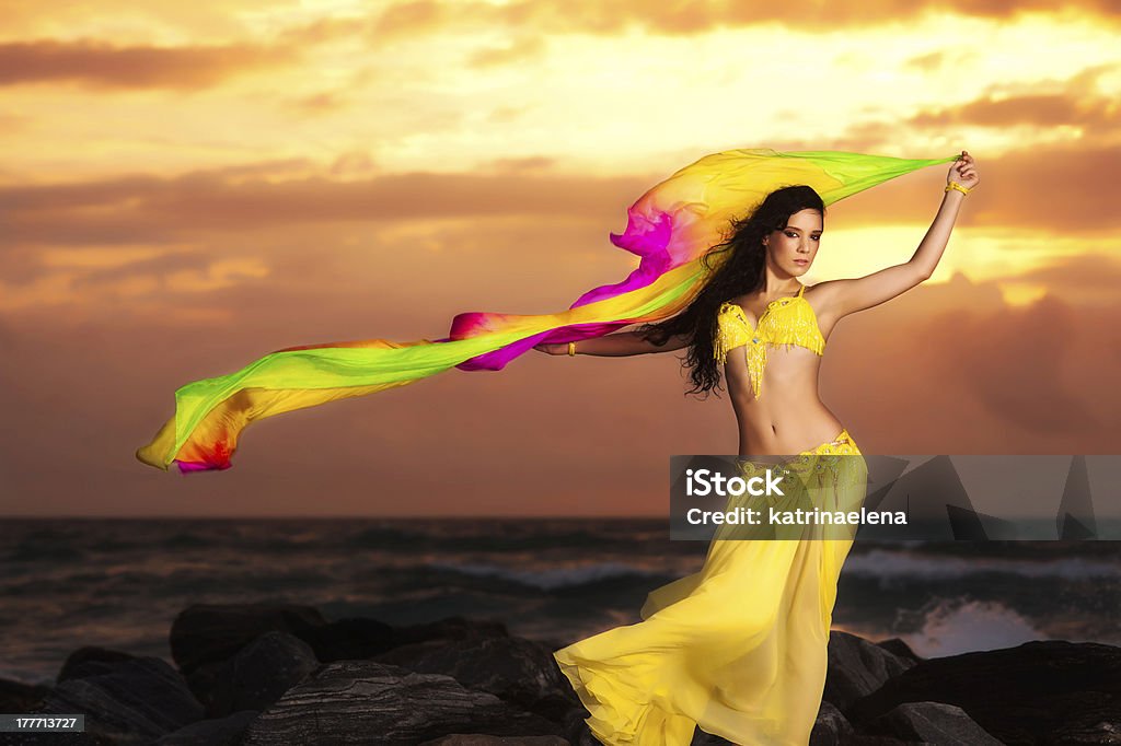 Исполнительница танца живота в желтый костюм на пляже на рассвете - Стоковые фото Танцевать роялти-фри