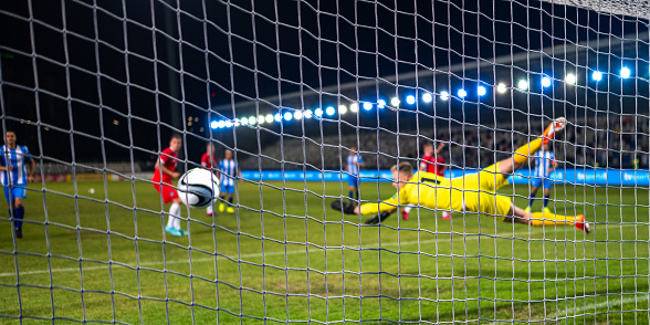 Soccer goalkeeper jumping and catching ball during sports match