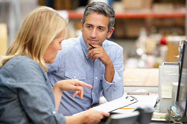 Business Colleagues Working At Desk In Warehouse Business Colleagues Working At Desk In Warehouse Having A Conversation warehouse office stock pictures, royalty-free photos & images