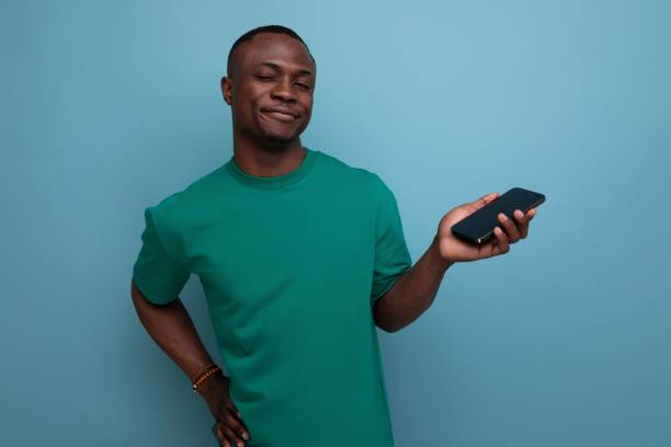 istock 30 year old handsome pleasant with dark skin american man dressed in a basic t-shirt holds a smartphone with his hand and smiles 1777163684