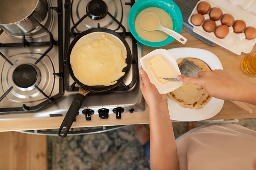 a woman makes pancakes on a griddle.