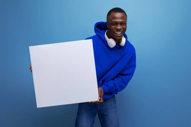 istock handsome young african man showing a white board with a mockup for advertising on the background with copy space 1777164840