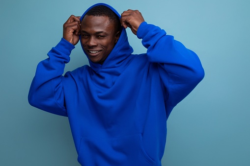 close-up portrait of a handsome dark-skinned 25-year-old American man in a stylish hoodie with a hood on his head against a background with copy space.