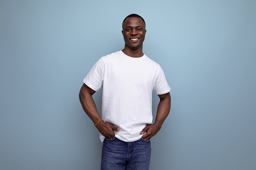 handsome young african man in white t-shirt on blue background with copy space.
