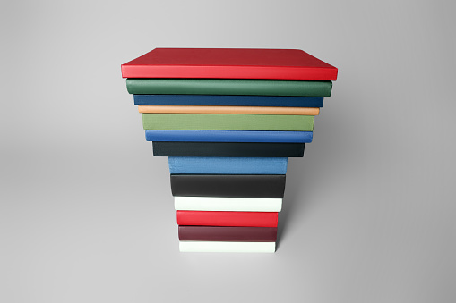 Stack of different hardcover books on light grey background
