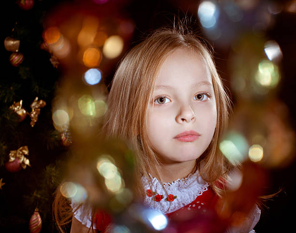 Little blond girl near chrictmas tree . Highlights colorful stock photo