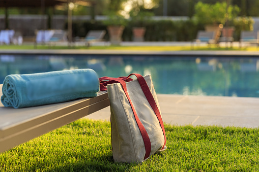 Grey Towel on relaxing pool bed beside swimming pool.