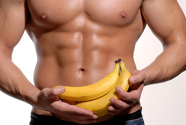 Abdominal fruit. Strong and fitness man holding a bunch of bananas. testosterone