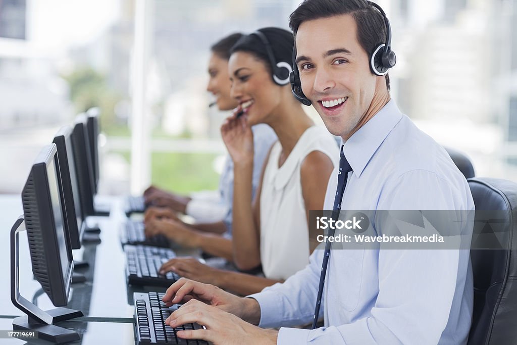 Joyful agent working in a call centre Joyful agent working in a call centre with his headset 20-29 Years Stock Photo