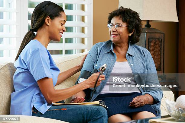 Visiting Nurse Taking Care Of A Patient Stock Photo - Download Image Now - Blood Pressure Gauge, Home Caregiver, Senior Adult