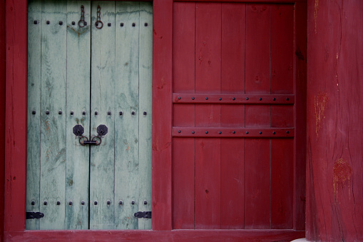Closeup of an old green wooden front door, with brass mail slot.
