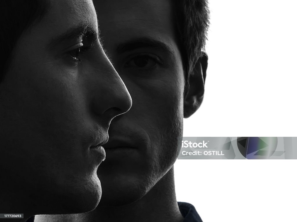 close up portrait two  men twin brother friends silhouette close up portrait  two caucasian young men in shadow  white background Men Stock Photo
