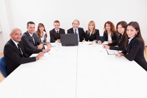 Businesspeople Sitting At Conference Table At The Meeting