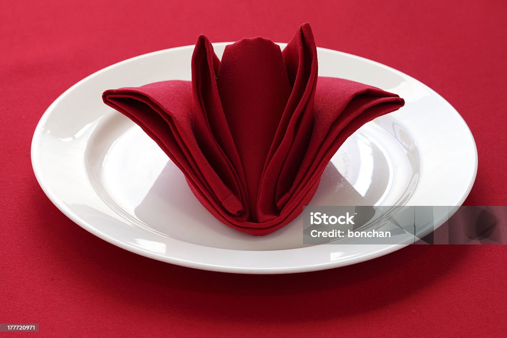 folded napkin like a rose bud table setting on red background Folded Stock Photo