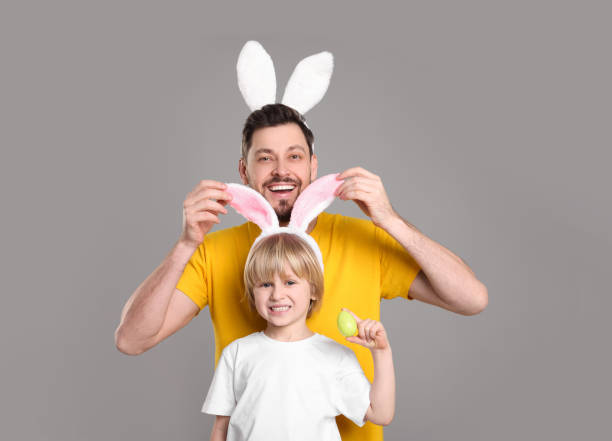 istock Father and son in bunny ears headbands having fun on grey background. Easter celebration 1777210512