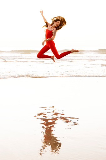 Female in a Red Outfit doing Yoga Stretching on the Beach