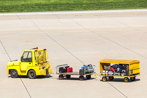 Yellow freight trolleys with loaded baggage on the runway tarmac