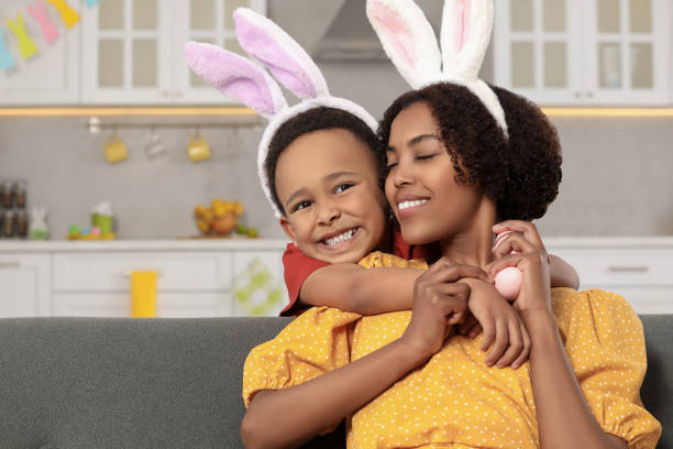szczęśliwa afroamerykańska matka i jej uroczy syn z pisankami w domu - easter rabbit sofa women zdjęcia i obrazy z banku zdjęć
