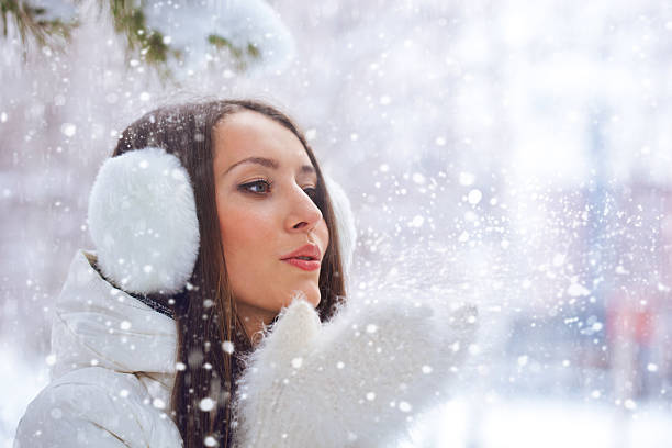 istock woman in winter park blowing on snow 177723793