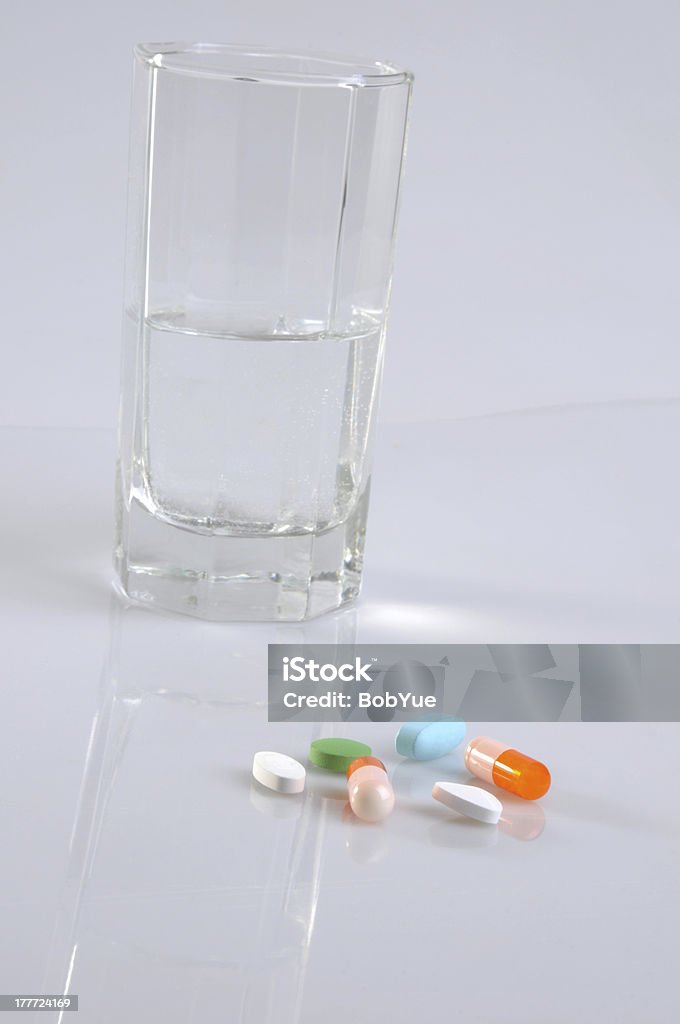 Medication time to Tablets and capsules as well as a glass of water on a white background . Antibiotic Stock Photo