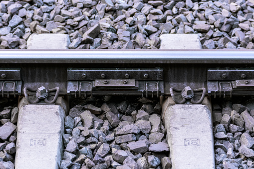 Fragment of a railway track with a steel rail and concrete sleepers covered with gravel.