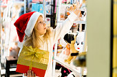 a little girl in a Christmas hat with a New Year's gift in her hands at a showcase with toys. children choose gifts for Christmas. Black Friday discounts