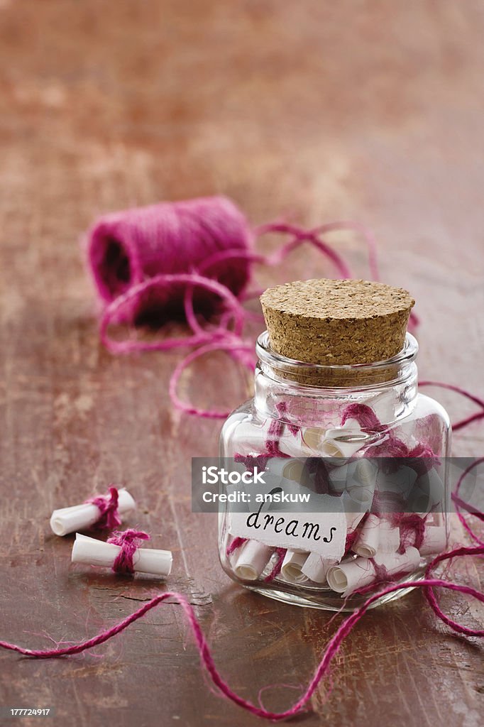 Jar full of dreams Dreams written on a white rolled paper in a glass jar on rustic vintage wooden background, dreaming optimism concept Aspirations Stock Photo