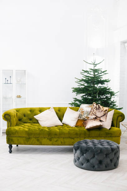 istock Classic green sofa with pillows and gray ottoman, christmas tree in an elegant luxury white living room 1777251154
