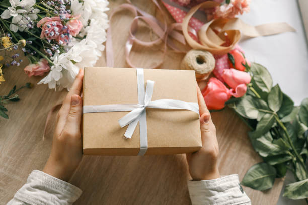 istock Gift box in hands with flowers at home 1777254628