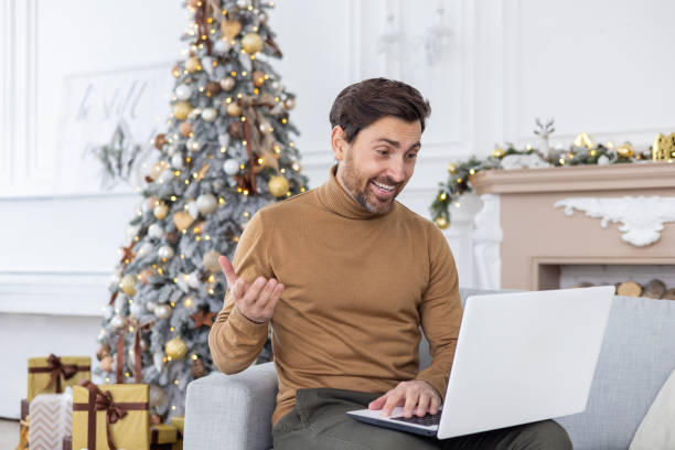 istock A young man is talking on a video call on a laptop while sitting on the sofa at home. Smiling and gesturing to the camera 1777260886