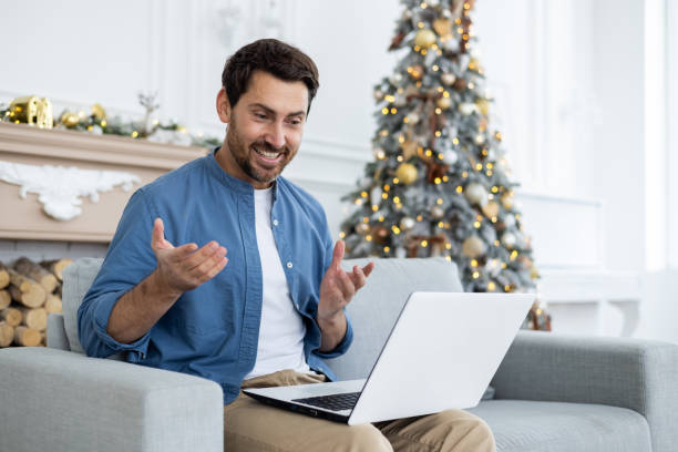 istock Young man talking on video call on laptop while sitting on sofa at home, smiling and gesturing with hands 1777261412