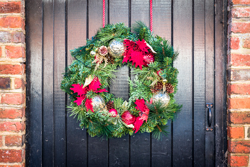 Detail of a Christmas wreath on an old black wooden door of a cottage, UK