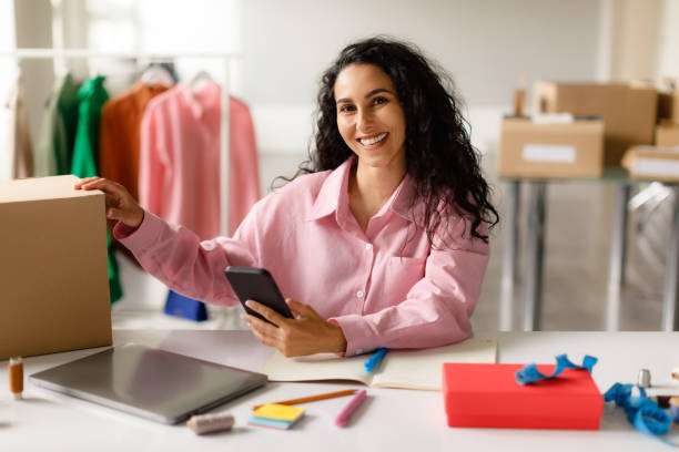 istock Middle Eastern Manager Lady Using Smartphone Packing Clothes In Shop 1777264324