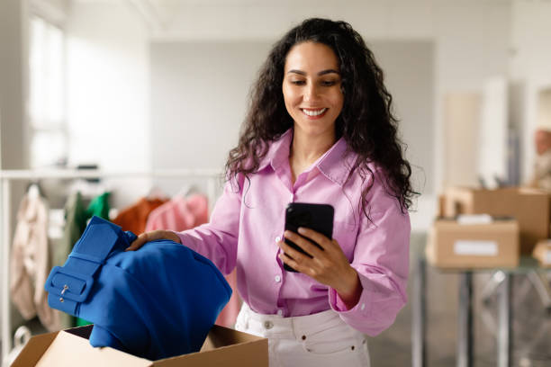 istock Designer Woman Using Smartphone Packing Garment For Delivery In Store 1777265495