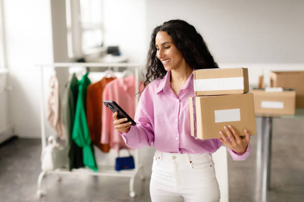 istock Lady messaging on smartphone holding packed boxes at clothes shop 1777265686