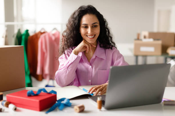 istock Cheerful Designer Lady Sitting At Laptop Computer In Clothes Store 1777266084